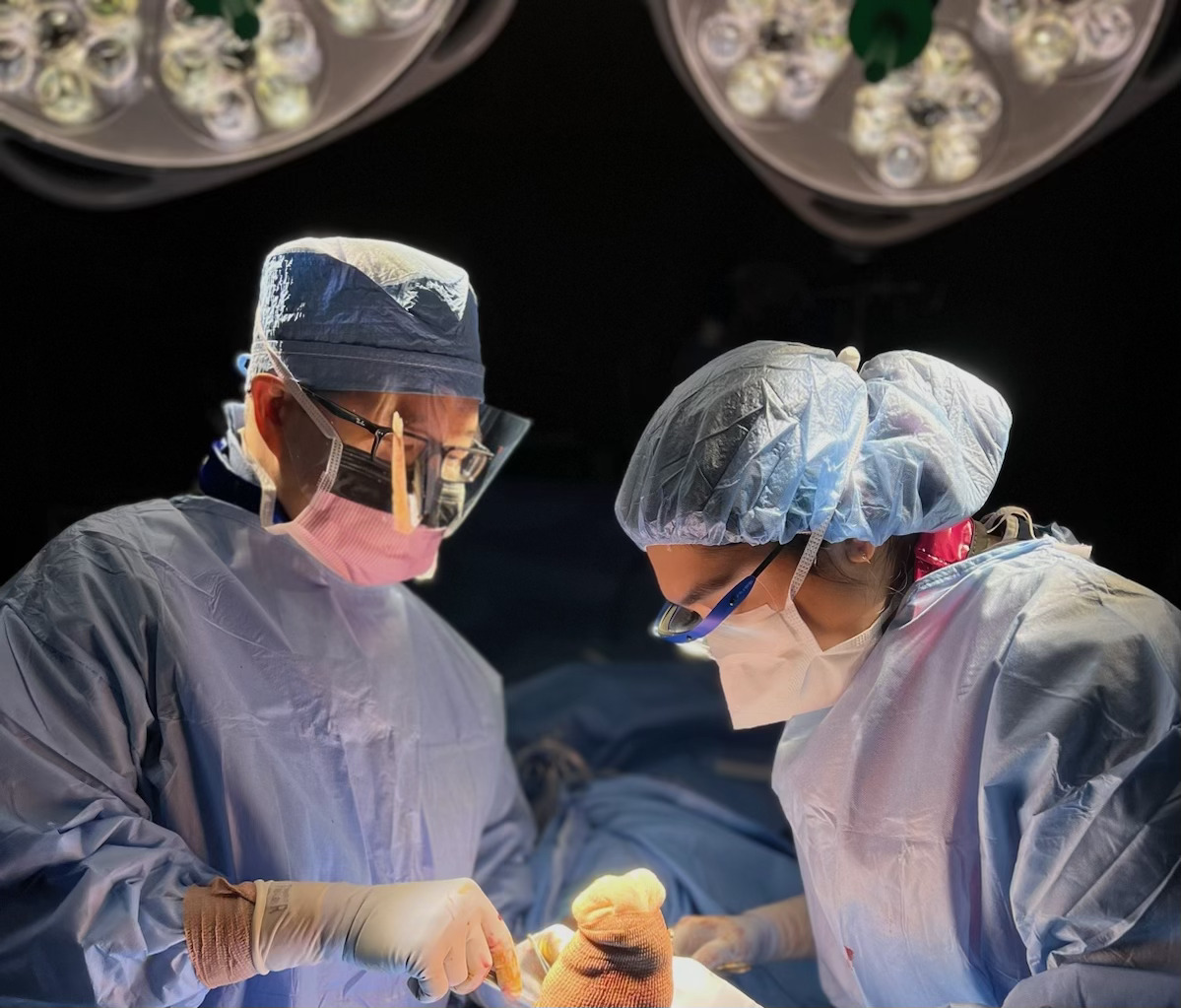 Dr. Nguyen performing surgery alongside a colleague under bright operating lights